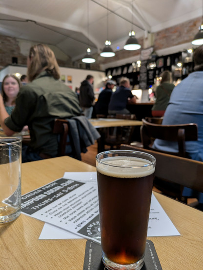 A glass of dark beer in a crowded bar