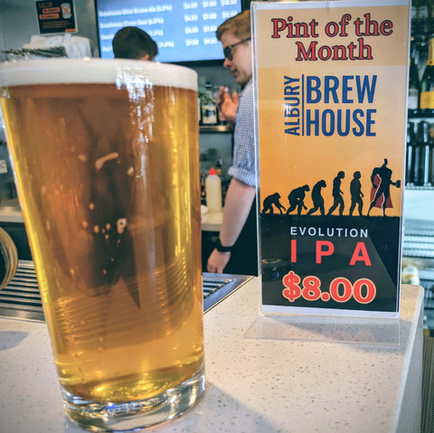 A pint of beer next to a sign saying pint of the month $8
